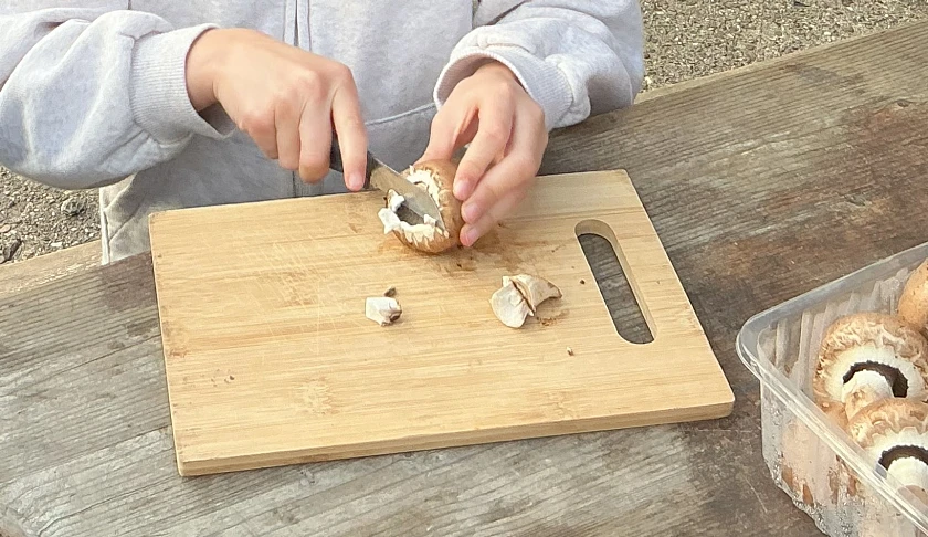 Hände, die einen Champignon schneiden