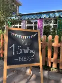 Kreidetafel vor dem Schulgarten. Auf der Tafel steht: 1. Schultag 15.08.2026